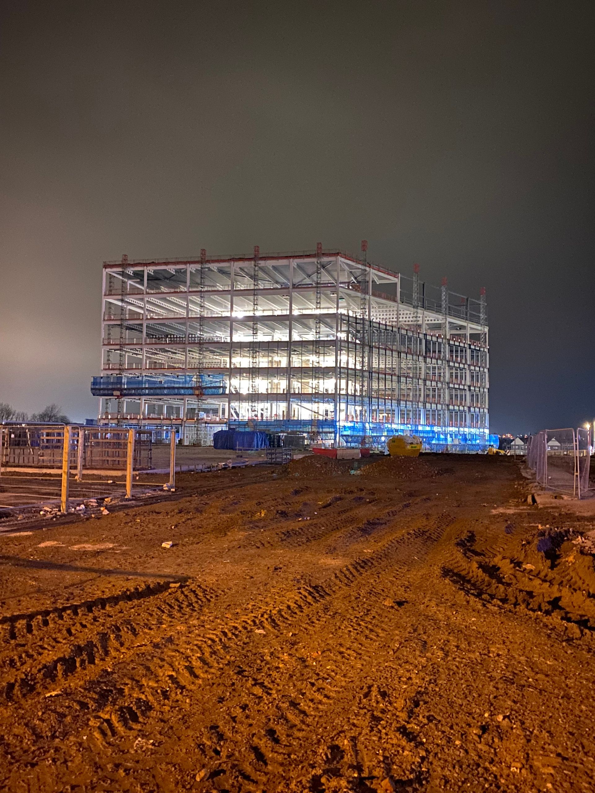 Illuminated building under construction at night in Leeds, capturing architectural progress.