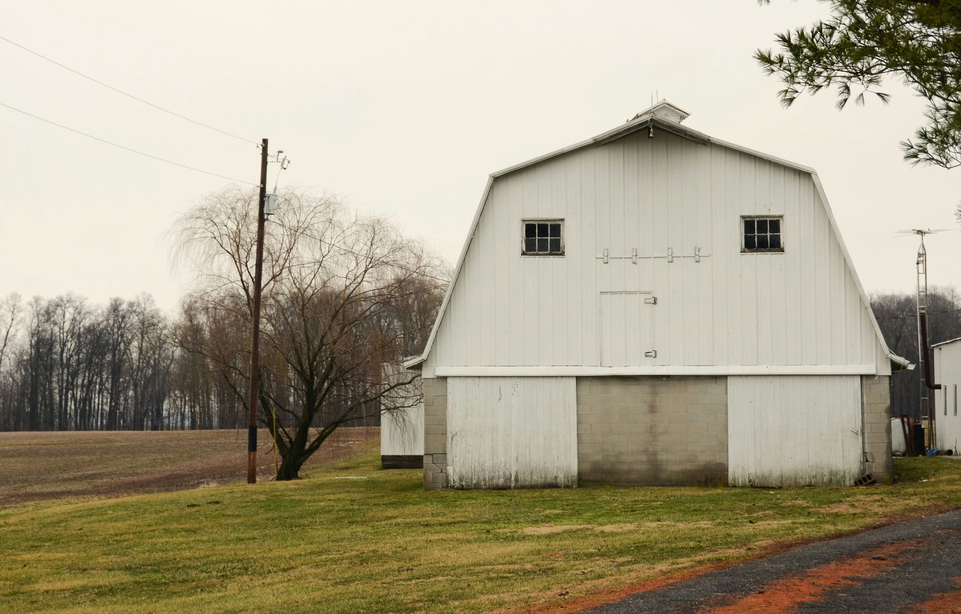 A white barn stands in a grassy field.